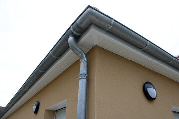 Gouttière zinc gris sur la façade de la maison, descentes et lambris de sous-face en PVC blanc