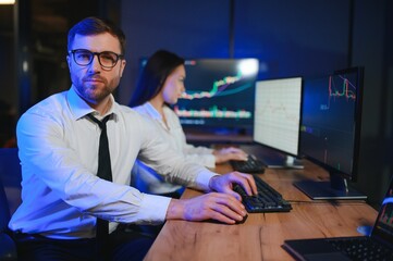 Team of traders working at monitor computer and browsing online in trading office