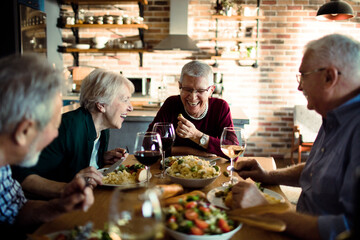 Happy senior people eating together at home