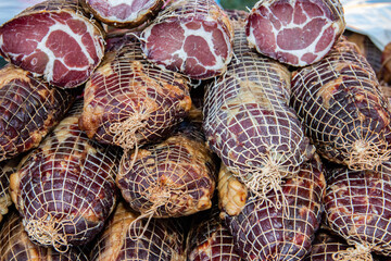 Delicious pieces of smoked meat exposed for sale in the market  presented for sale on a farmer's market in Kacarevo village, gastro bacon and dry meat products festival called Slaninijada (bacon fest)