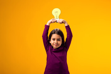 Thoughtful child girl holding paper bulb above head. Success, motivation, winner, genius, idea concept