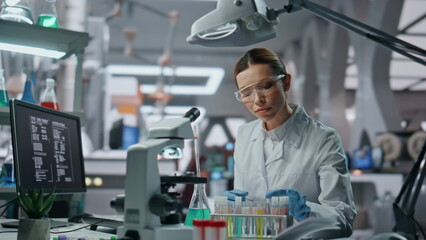 Biochemistry specialist checking samples in beaker working in laboratory closeup