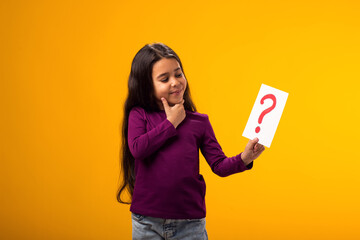 Thoughtful kid girl holding question mark card. Children, idea and knowledge concept