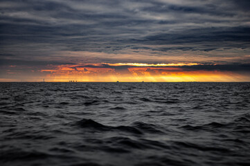 Dark seascape with golden sunset on the horizon