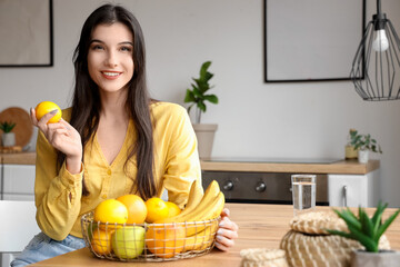Obraz premium Pretty young woman with fresh fruits in basket at home