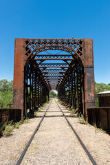 man walking on an old iron bridge over the train tracks 