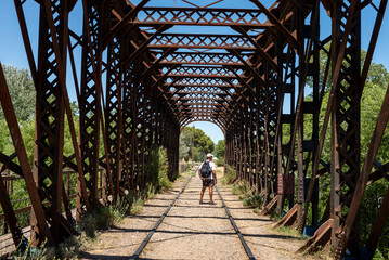 man walking on an old iron bridge over the train tracks 