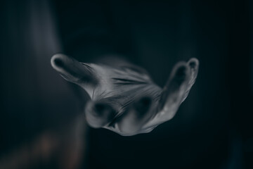 Hand in a black glove hovers over a black background