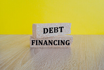 Debt financing symbol. Concept words Debt financing on brick blocks on a beautiful wooden table yellow background. Business finance and debt financing concept