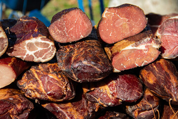Delicious pieces of smoked meat exposed for sale in the market  presented for sale on a farmer's market in Kacarevo village, gastro bacon and dry meat products festival called Slaninijada (bacon)