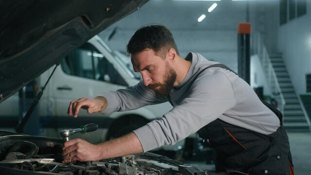 Auto mechanic tired Caucasian man vehicle service manager technician open automobile hood bonnet fixing engine with spanner key tool repair broken truck in garage workshop male exhausted overworking