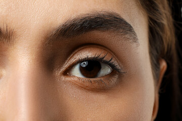 Young woman with brown eyes on dark background, closeup