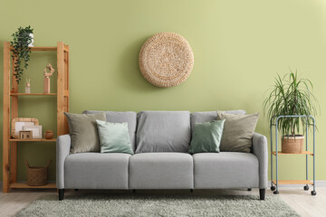 Interior of stylish living room with grey sofa, pouf and shelf unit