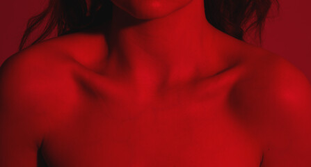 Female body in red lighting. Women's shoulders and collarbones