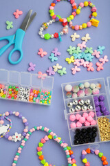 Box with beads to create hand made jewelry for child on violet background. Making bracelet. Handmade accessories. Vertical photo