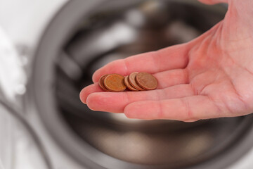 Coins in hand in laundry closeup. Commercial routine