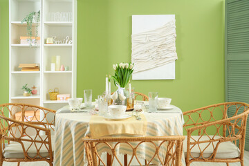 Table setting with tulip flowers for International Women's Day celebration in stylish room near green wall
