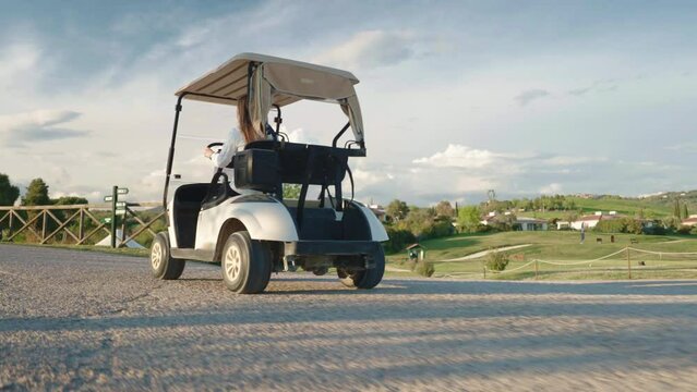Woman riding luxury golf cart to arrive on place for playing sport game, golf cart for two people in motion against amazing golf course and countryside background