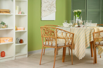 Table setting with tulip flowers for International Women's Day celebration in stylish room near green wall
