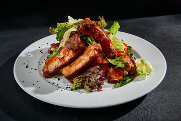 BBQ ribs with a mixed salad garnish on a white plate