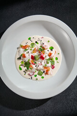 Burrata cheese with tomatoes and cilantro, top view on a dark background