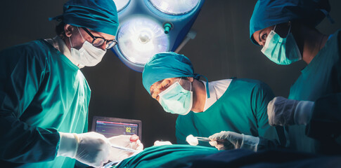 Professional Medical Doctors and team performing surgical operation in bright Modern operating room...