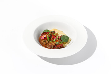 Braised beef with vegetables and mushrooms served with mashed potatoes, on an isolated white background, a hearty meal