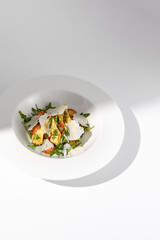 Salad with artichokes and tomatoes with Parmesan cheese, shadowed on a white plate