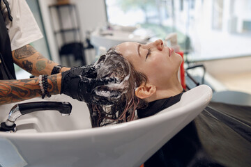 Close up of hairdresser is washing hair of young woman in beauty salon. High quality photo 