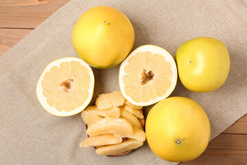 Tasty whole and cut pomelo fruits with pieces on wooden background