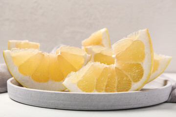 Plate with sweet pomelo slices on light background