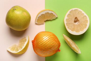 Tasty whole and cut pomelo fruits with slices on colorful background