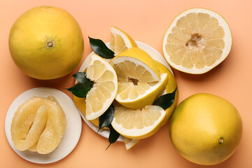 Tasty whole and cut pomelo fruits with slices on orange background