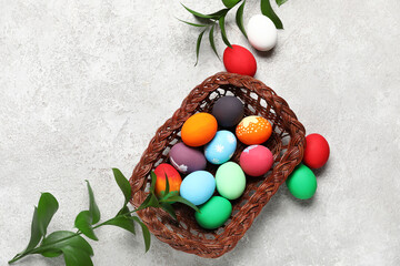 Basket with painted Easter eggs and green branches on grey grunge background