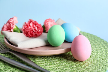 Beautiful festive table setting for Easter with colorful eggs and flowers on blue background