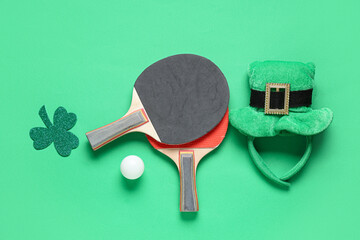 Ping pong rackets, clover and leprechaun's hat on green background. St. Patrick's Day celebration