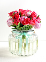 Obraz premium Beautiful pink peony flowers bouquet in glass vase on white background