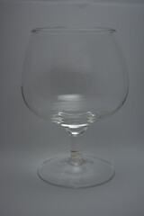 A stylish glass for cognac, brandy, whiskey is located on a white glossy background.