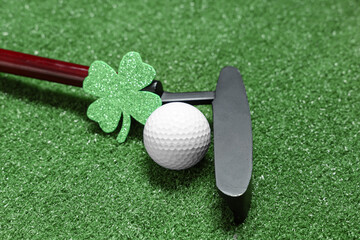 Golf club, ball and clover on green grass background. St. Patrick's Day celebration