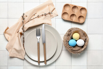 Beautiful table setting for Easter with eggs and willow branches on white tile background