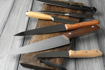 Many different knives and board on light wooden table