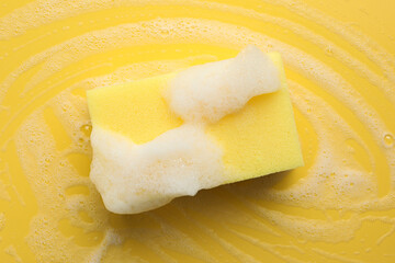 Sponge with foam on yellow background, top view