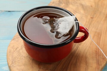 Tea bag in cup with hot drink on light blue wooden table, closeup