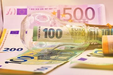 Light bulb on, with banknotes, coins and energy bill. Increase in energy and gas tariffs. Efficiency and energy saving.