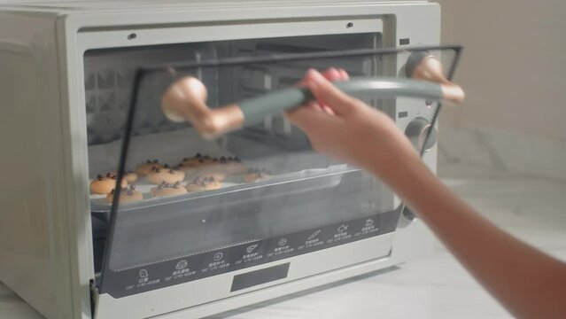 Cropped shot of girl setting oven temperature when baking cookies with chocolate chips