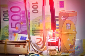 Stethoscope with euro banknotes in the background, health care costs concept