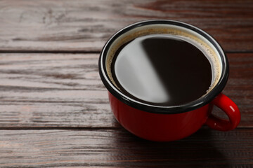 Cup of aromatic coffee on wooden table, closeup. Space for text