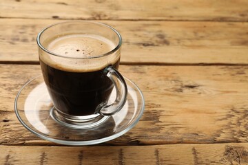 Cup of aromatic coffee on wooden table, closeup. Space for text