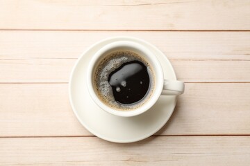 Cup of aromatic coffee on light wooden table, top view