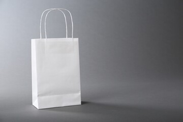 One white paper bag on grey background, space for text. Mockup for design